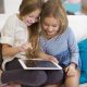Mergaitės sėdi ant sofos ir žiūri iPad