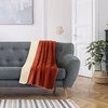 Oranžinė ir kreminė lovatiesė ant sofos
