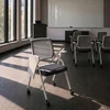Tamsiai pilka biuro konferencijų kėdė su rašomuoju stalu ant ratukų ir baltomis kojomis