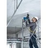 Darbininkas gręžia lubas su Bosch GBH 18V-24 C perforatoriumi