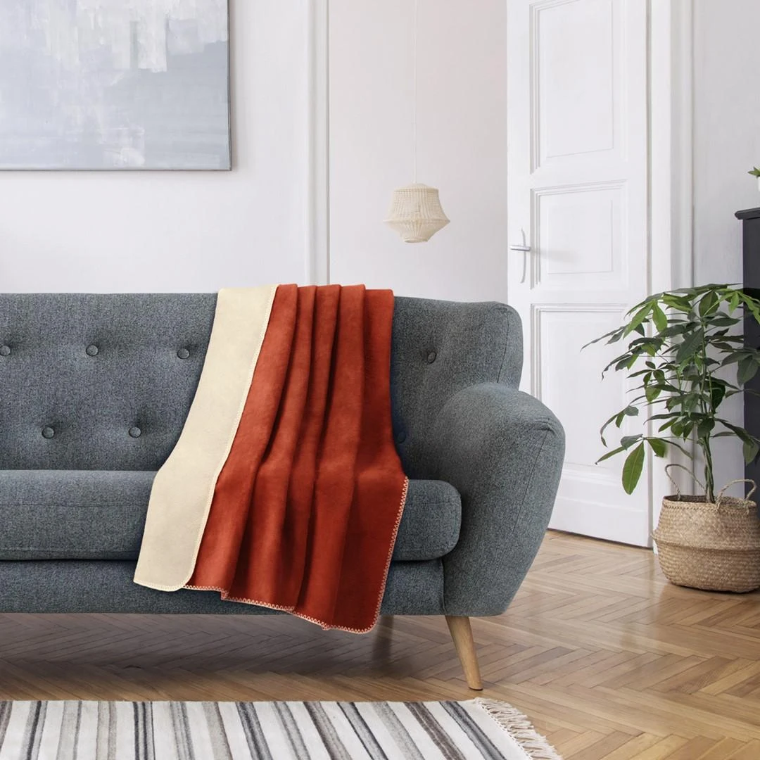 Oranžinė ir kreminė lovatiesė ant sofos