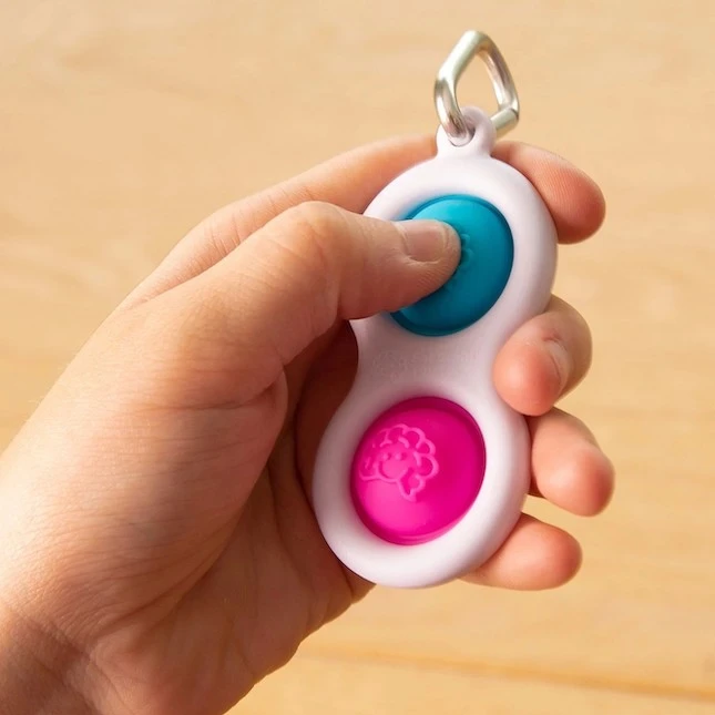 Fat Brain Toys Sensorinis žaislas - raktų pakabukas „Simpl Dimpl“ (įvairių spalvų)