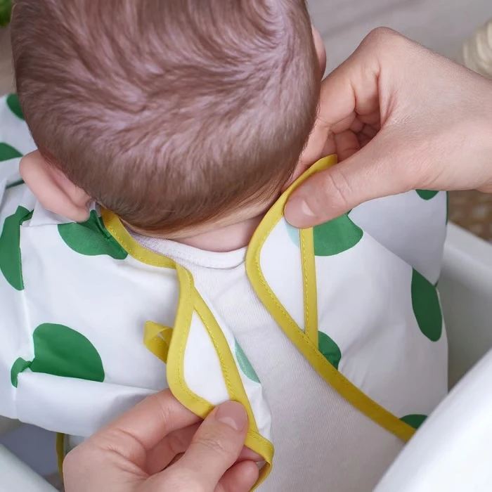 IKEA KLADDIG Prijuostės seilinukas su rankovėmis, baltais ir žaliais taškeliais