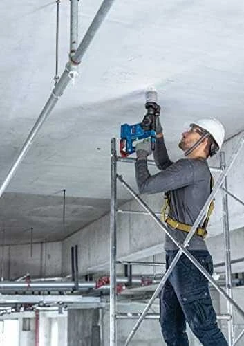 Darbininkas gręžia lubas su Bosch GBH 18V-24 C perforatoriumi
