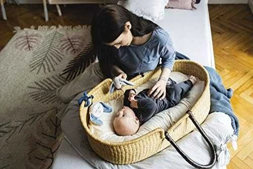 Kūdikis su dūzgiančiu žaislu pintoje lovelėje