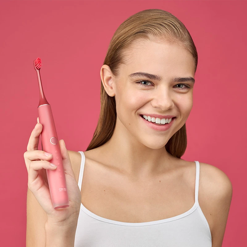 Osom Oral Care rožinis garsinis dantų šepetėlis rankose