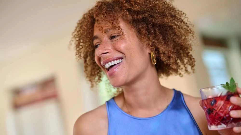 Philips Sonicare antgaliai – besišypsanti moteris su gėrimu