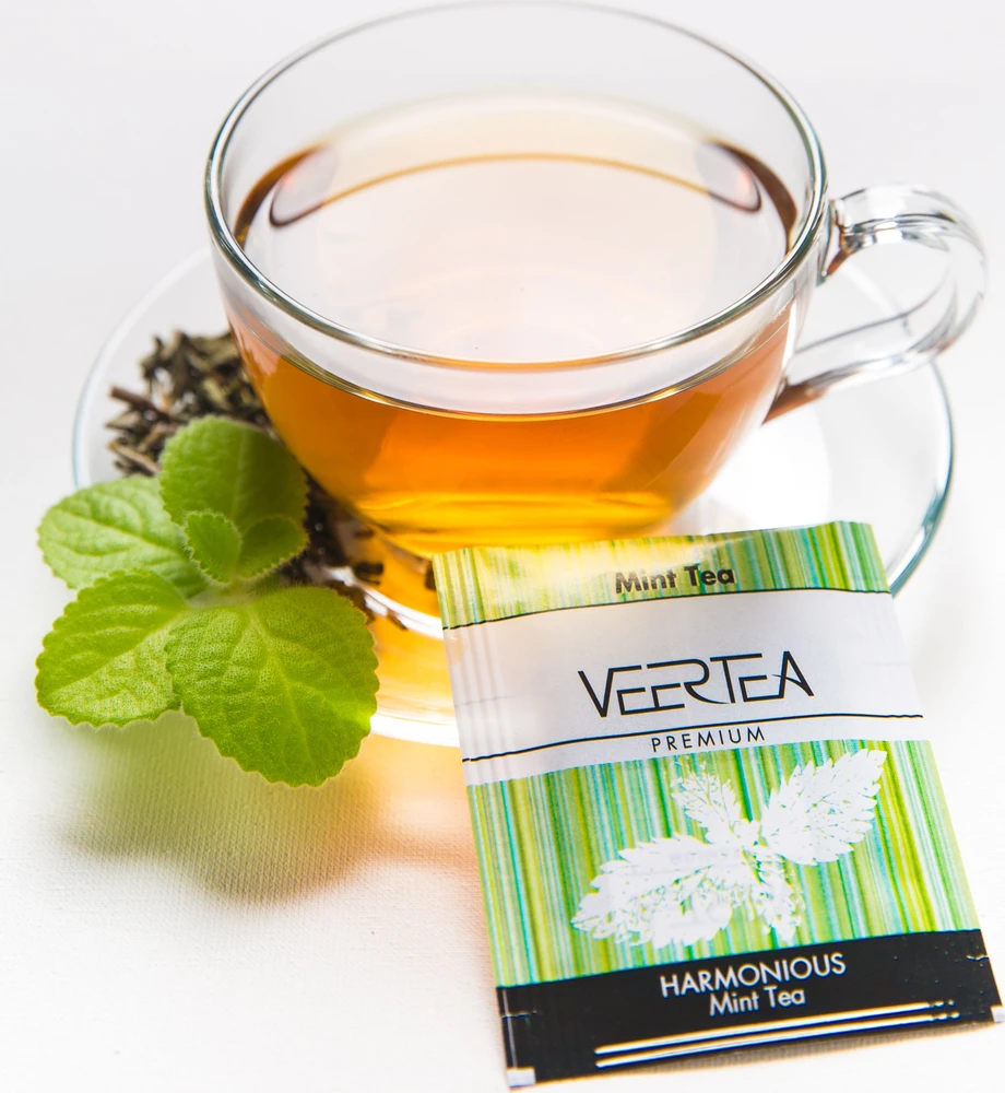 Veertea mėtų arbata puodelyje su šviežiais lapeliais